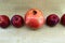 Four red apples and one big red pomegranate lie in a row