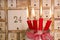 Four red burning advent candles with calendar.