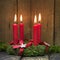 Four red burning advent candles on a wreath.