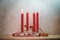 Four red candles, one is lit for the first Sunday before Christmas, Advent decoration on a wooden table against a rustic wall,