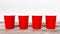 Four red empty take away disposable paper cups on wooden desk and white background