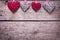 Four red and grey rustic decorative hearts on vintage wooden b