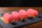 Four red mini mousse cakes in shape of candy on dark stone