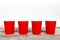 Four red paper disposable cups for coffee and nonalcoholic drinks on wooden background