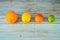 Four ripe citruses, orange, lemon, small grapefruit and lime lie in a row on an old wooden table