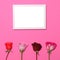 Four roses on pastel pink background with blank photo frame above - Trendy minimal flat lay concept