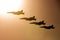 Four Royal Australian Air Force RAAF Boeing F/A-18F Super Hornet multirole fighter aircraft flying in formation at sunset.