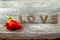 Four rustic alphabet blocks spelling out Love with red rose on wood