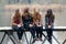 Four school girls sitting on river bridge