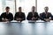 Four serious confident businessmen sitting at table in boardroom