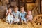 Four siblings sit on hay in a rustic barn surrounded by wooden crates and a barrel