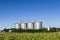 Four silver silos in field under blue sky