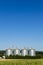 Four silver silos in field under blue sky