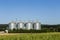 Four silver silos in field under blue sky