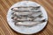 Four silvery brushed mullets lie surrounded by fine ice, on a white plate