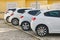 Four similar white hatchback cars parked on street in typical European town