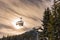 Four skiers on a chair lift against the backdrop of the sun and trees, contour photo, orange shades, ski region Schladming Austria