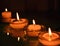 Four small candlesticks with burning even flame candles on a smooth surface