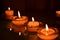 Four small candlesticks with burning even flame candles on a smooth surface