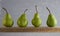Four small pears on wooden board.