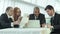 Four smiling successful businessmen sitting at table in office