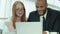 Four smiling successful businessmen sitting at table in office while discussing