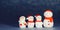 Four snowman figures on a shiny paper background. Christmas decorative smiling snowmen. Horizontal banner.