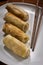 Four spring rolls in a plate with chopsticks .