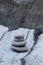 Four stacked stones on rock at waters edge, space for text