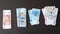 Four stacks of banknotes located on the brown table, dollars, euro, hryvnia, rubles. Cash banknotes. The concept of