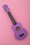 Four string ukulele guitar on pink background