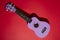 Four string ukulele guitar on red background