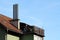 Four tall chimney pipes on top of old suburban family house next to top balcony with dilapidated wooden fence filled with stuff