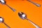 Four teaspoons laid out on an orange background