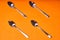 Four teaspoons laid out on an orange background