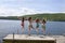 Four teenage girls jumping off dock at lake