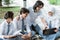 four teens in high school uniform use a laptop doing group assignment sitting