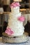 Four tier wedding cake with fondant ruffles and pink edible roses.