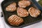 Four toasted steaks on a grilled pan, with finely chopped rosemary.