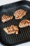 Four toasted steaks on a grilled pan, with finely chopped rosemary.