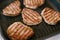 Four toasted steaks on a grilled pan, with finely chopped rosemary.