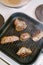 Four toasted steaks on a grilled pan, with finely chopped rosemary.