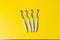 Four toothbrushes lie on a yellow background.