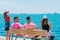 Four tourist couples sitting on a bench and enjoying the breathtaking sea view