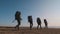 The four travelers with backpacks walking on the seascape background.