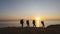 The four travelers with backpacks walking on the seascape background.