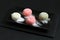 Four types of Japanese dessert mochi - pomegranate with honey, green matcha tea, strawberry, coconut on a black plate