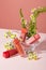 Four unbranded lipsticks are displayed alongside daisies and fern leaves on a pink background. Concept of homemade cosmetics with