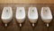 Four urinals lined up on the tiled wall of a modern men`s public toilet, no privacy