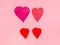 four various hearts cut from red papers on pink